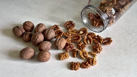 Slow Motion Walnuts and Walnut Kernels Spilling from a Glass Jar Stock Footage 344577505