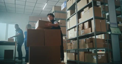 Slow motion of warehouse associate taking cardboard parcel from the shelf Stock Footage 307580114