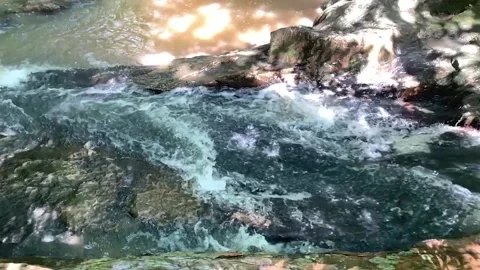 SLOW MOTION- WATER CASCADING OVER AND BETWEEN ROCKS IN A STREAM Vídeos de archivo 131336956