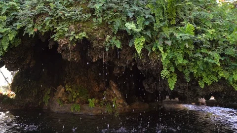 Slow motion water dripping from the underside of natural rock formation Stock Footage 119327938