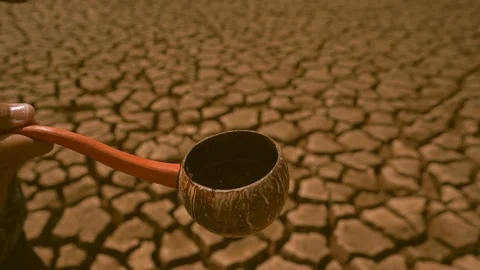 Slow motion water droplet falling in water dripper on cracked earth background Video stock 124865492