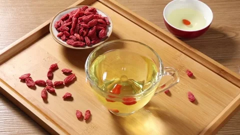 Slow Motion Water Droplet Falling into Goji Berry Tea in Glass Cup Stock Footage 340303291