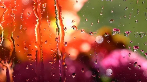 Slow motion of water flowing down window glass with colorful defocused view Video stock 99145147