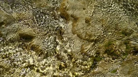 Slow motion: water flowing over rocks in a mountain riverbed in summer sunlight. Stock Footage 211744674