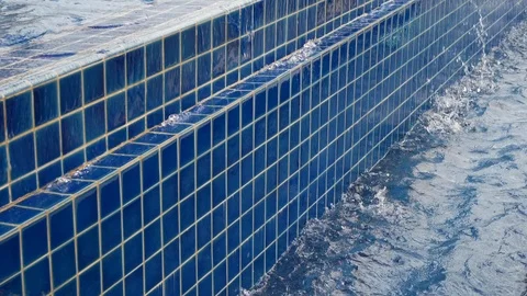 Slow motion water flowing overflow blue swimming pool Stock Footage 91587565