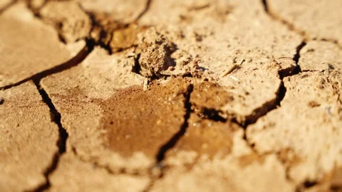 Slow motion water hitting parched cracked earth during extreme heat and drought Video stock 310984258