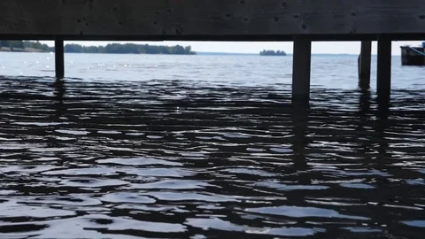 Slow motion water in motion. POV at lake surface with dock in summer. Stock Footage