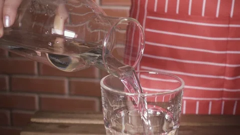 Slow motion water pours from the decanter into a glass of female hands Stock Footage 88469744