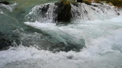 Slow motion of water running over rocks of a mountain stream Video stock 260868681