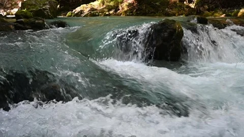 Slow motion of water running over rocks of a mountain stream Video stock 260868803