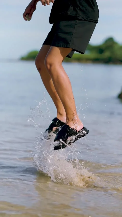 Slow Motion Water Splash from Footsteps at the Shore. man splashing water w.. Stock Footage 307700790