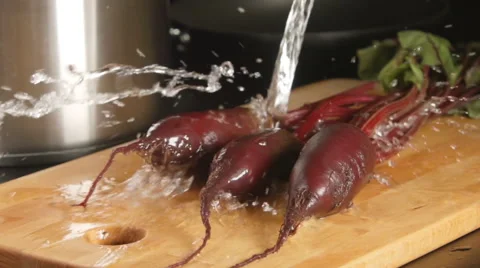 SLOW MOTION: Water stream falls on a beets on a cutting board in a kitchen Stock Footage 68155823