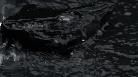 Slow motion water surface texture splashes, waves and ripples with black stone Stock Footage 278256445