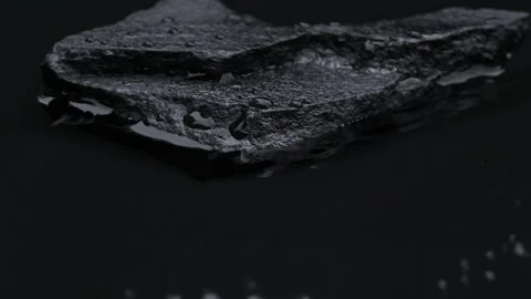 Slow motion water surface texture splashes, waves and ripples with black stone Video stock 282504483