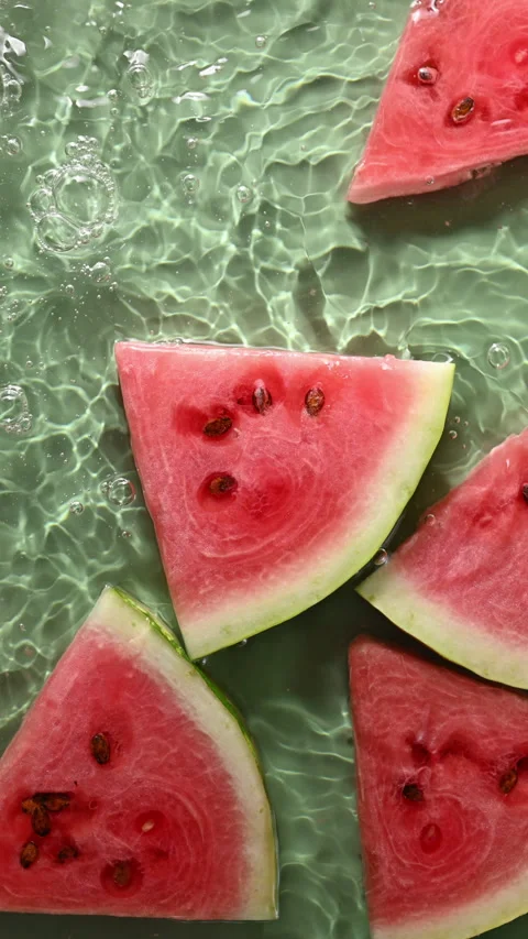 Slow-motion water waves rock juicy watermelon slices on green background. Stock Footage 315877307