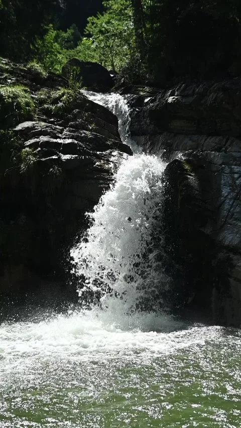 Slow motion of a waterfall in direct midday sunlight, vertical shot Stock Footage 260870139