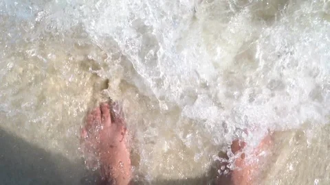 Slow motion of wave breaking on feet standing on sand at beach Stock Footage 106370317