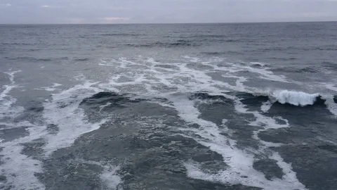 Slow-motion wave crashes as camera pulls backwards at dusk Stock Footage 112703816