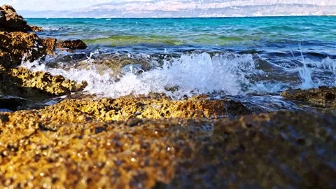 Slow motion wave crashing on rocks, low angle reverse shot. Stock Footage 316615325