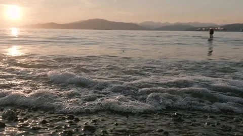 Slow motion of wave during sunset and woman being in the ocean 動画素材 136711241