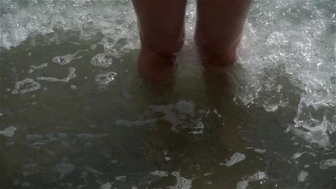 Slow motion of a wave on legs standing in the water. Stock Footage 114293828