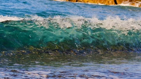 Slow motion wave receding along pebbleed beach into clear water as new shoreb Vídeos de archivo 108007580