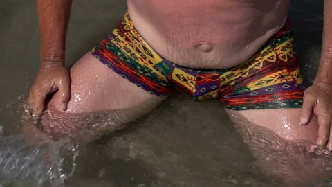 Slow motion of a wave running on a man sitting Stock Footage 113354726