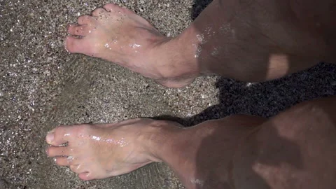 Slow motion wave washes and splashes about man's legs Stock Footage 112935853