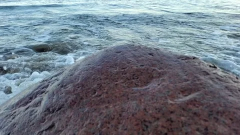 Slow motion waves behind a large rock 動画素材 332717969