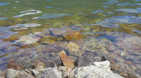 Slow Motion Waves Break on a Rocky Riverbank Stock Footage 65515371
