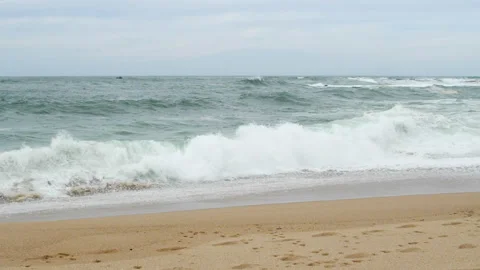Slow motion waves breaking on beach in winter with dull gray sky. Stock Footage 274176105