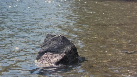 Slow motion waves breaking on a large rock in the water. Stock Footage 88644495