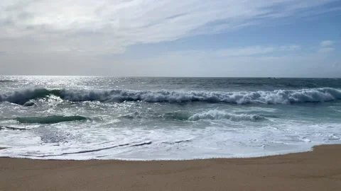 Slow motion waves breaking on sandy beach in Spring, with bright sunlight 動画素材 240671449
