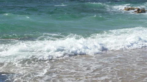 Slow motion waves breaking on sandy beach on a bright sunny day in Portugal. Stock Footage 273656737