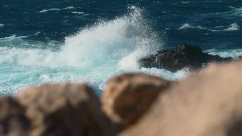 Slow motion waves crash against large rock on Malta coast, turquoise water Video stock 332483230