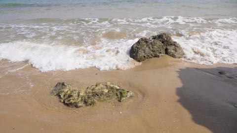 Slow motion waves crash around a rock Video stock 130871056