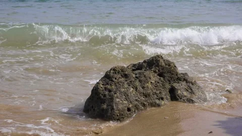 Slow motion waves crash over rock on beach Stock Footage 130870954