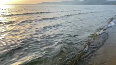 Slow motion of waves crashing on golden beach at sunset. Sea waves splashing on Stock Footage 201320221