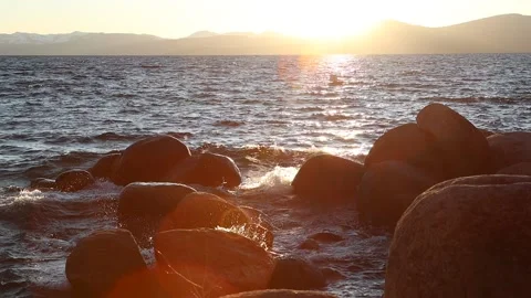 Slow motion waves hitting rocks at sunset sun flared Sand Harbor Lake Tahoe Stock Footage 134490443