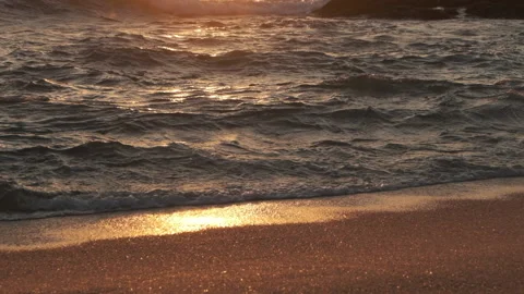 Slow motion waves lapping on sandy beach at sunset Video stock 131887159