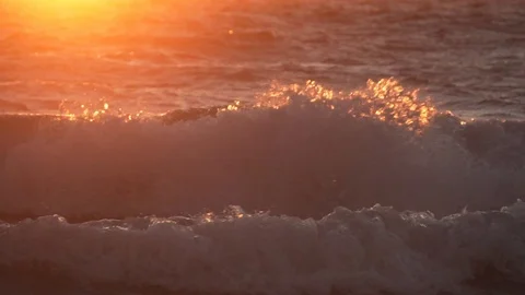 Slow motion of waves lit by beautiful orange sunlight close to sunset Video stock 119116135