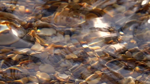 Slow motion of waves on shallow pure water with brown pebble bottom close up. Stock Footage 98096104