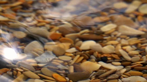 Slow motion of waves on shallow pure water with brown pebble bottom close up. Stock Footage 98096425