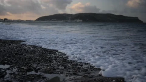 Slow motion waves on stoney beach at magic hour, LLandudno. Video stock 150289949