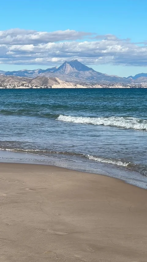 Slow motion of waves washing shore with distant mountains in Alicante Stock Footage 295206760