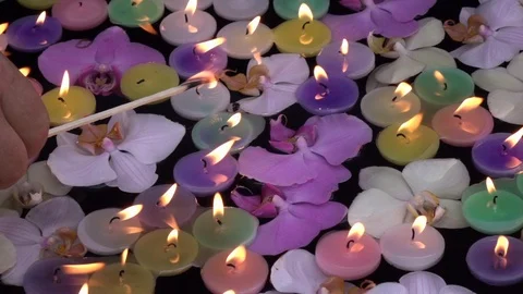 Slow motion of waving candle flames, floating among orchid flowers on dark water Video stock 99851289