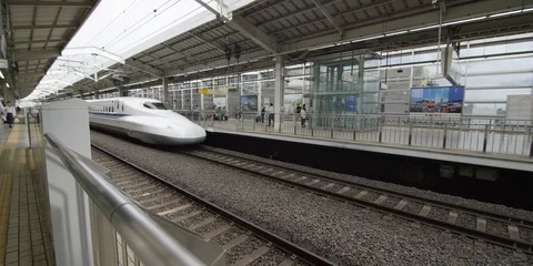 Slow motion of white fast train leaving train station with people in back, Tokyo Stock Footage 136112777