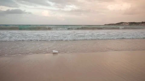 Slow motion of white foam cup on the sand on the seashore floating on the waves Stock Footage 244803438