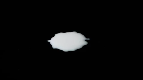 Slow motion as white milk is dripping on a black background. Drops of milk Stock Footage
