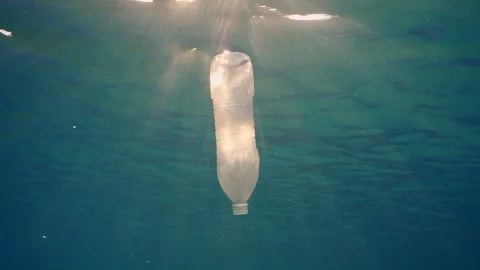 Slow motion, White plastic bottle drift under surface of water in sunrays Stock Footage 243988082